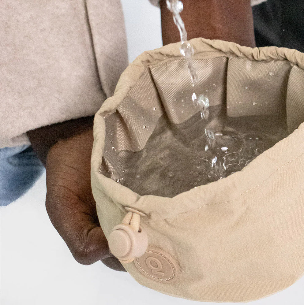Mensch füllt Wasser in den Napf von Qisu - Pocket Bowl in der Farbe: Beige.